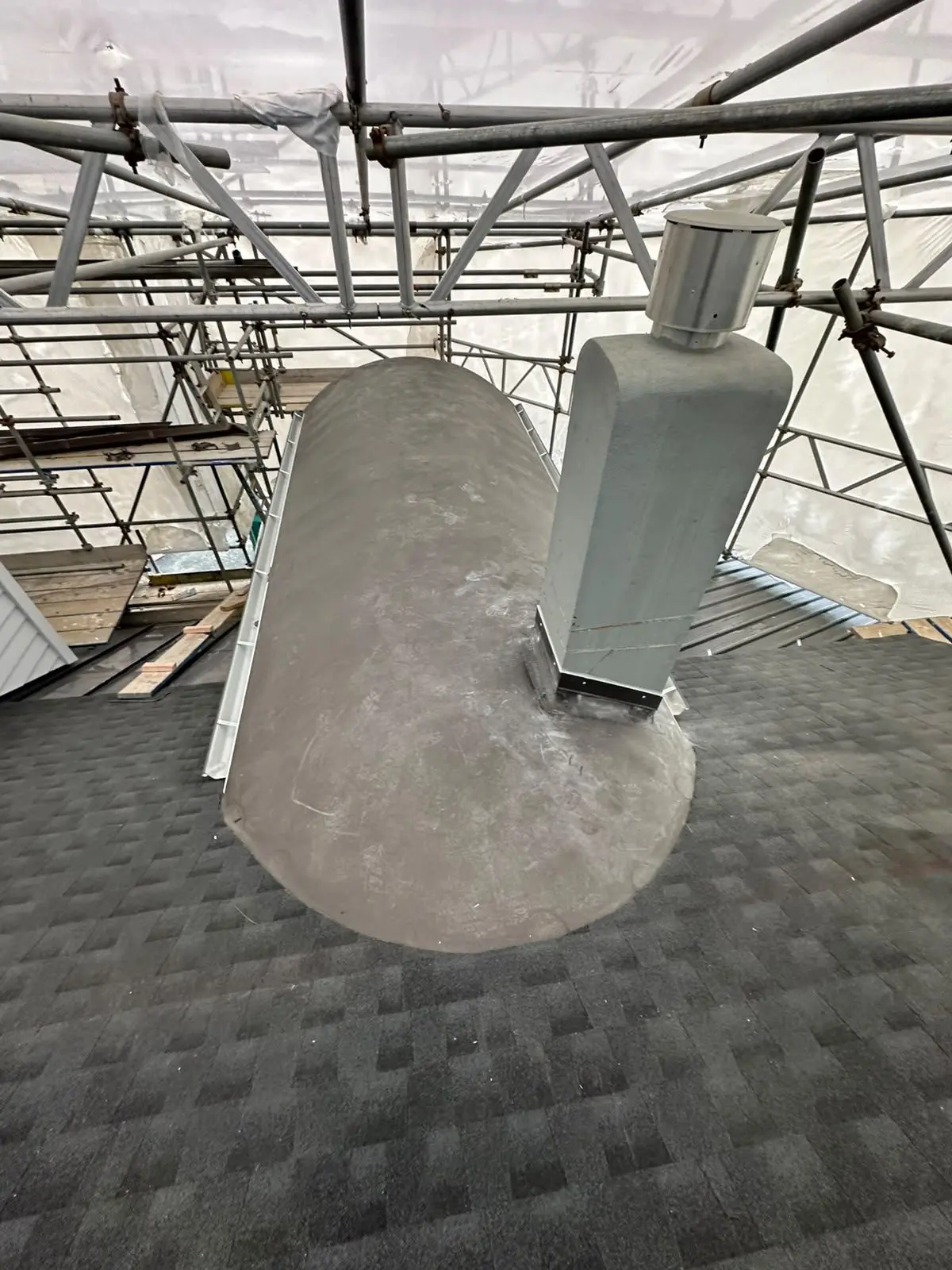 Flue penetration flashed on a shingle roof with a formed saddle